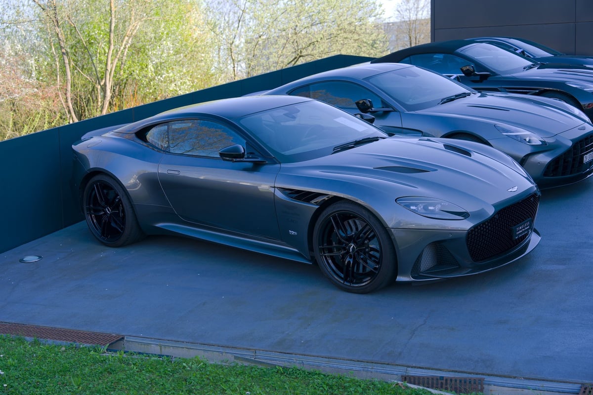Luxury Aston Martin sports cars displayed at premium automotive dealership under bright showroom lighting