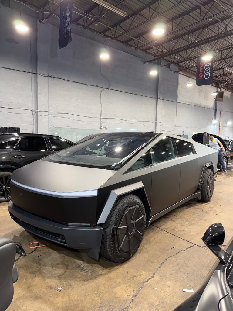 Tesla Cybertruck with stainless steel and black exterior parked in a warehouse showroom