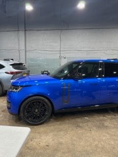 Blue SUV parked in a warehouse with a white vehicle visible in the background