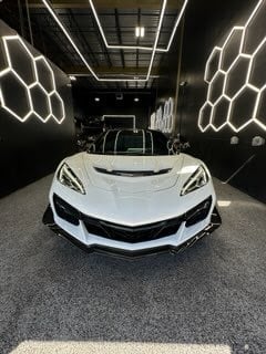 White sports car displayed in modern showroom with geometric neon lighting on black walls