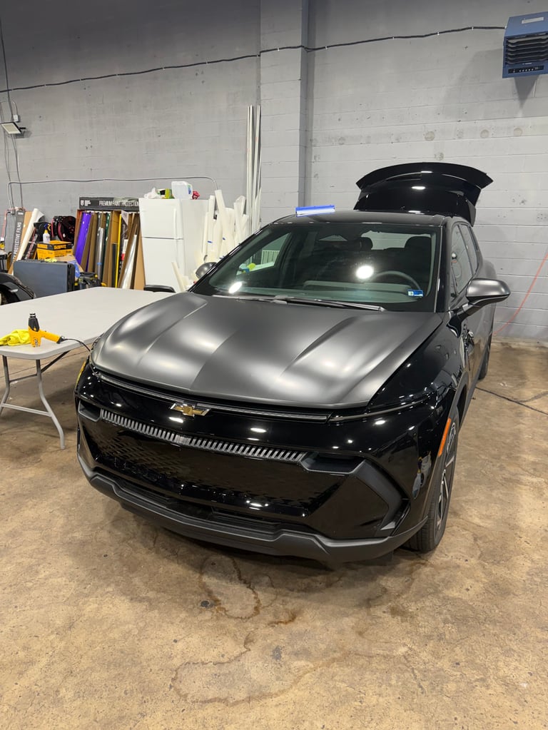 Black Chevrolet SUV with open roof cargo box in an indoor garage or workshop setting
