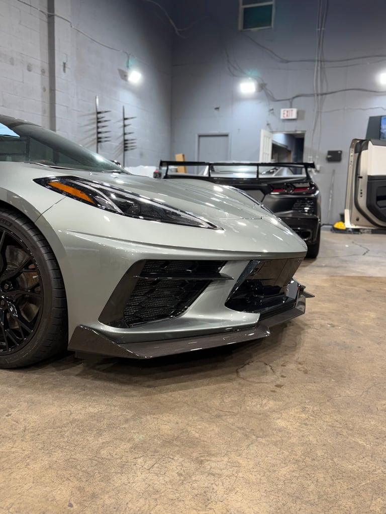 White sports car parked in auto repair shop garage with gray concrete floor and industrial lighting