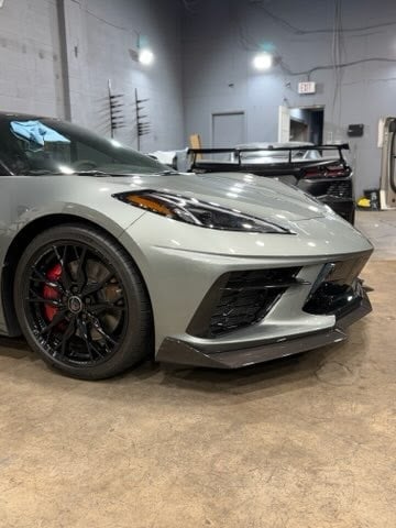 White sports car with black wheels and red brake calipers parked in an indoor garage workshop