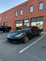 Black sports car parked in front of a red brick building with storefront windows