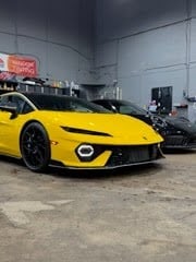 Bright yellow sports car with black accents parked in an industrial garage setting